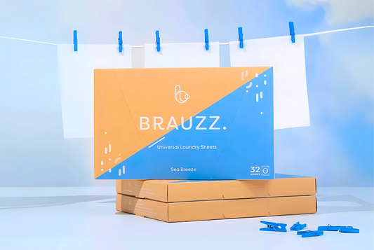 Brauzz wasstrips oceaan pakket op 2 andere doosjes wasstrips met wasknijpers voor en wasstrips die vasthangen op een wasdraad met blauwe wasspelden op de achtergrond. De hele afbeelding is omringt door prachtige blauwe lucht