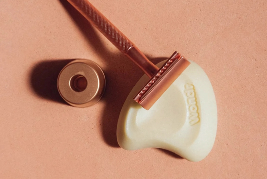 Roze ijzere WONDR scheermesjes met een houder op de shaving bar van WONDR allemaal in een bruine setting