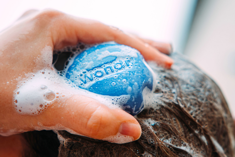 Persoon die zijn/haar haren aan het wassen is met een blauwe shampoo bar van Wondr