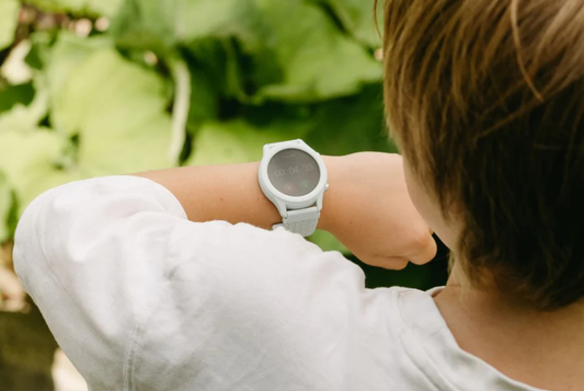 achteraanzicht waarbij we over de schouder van een kind meekijken naar de horloge op zijn pols 