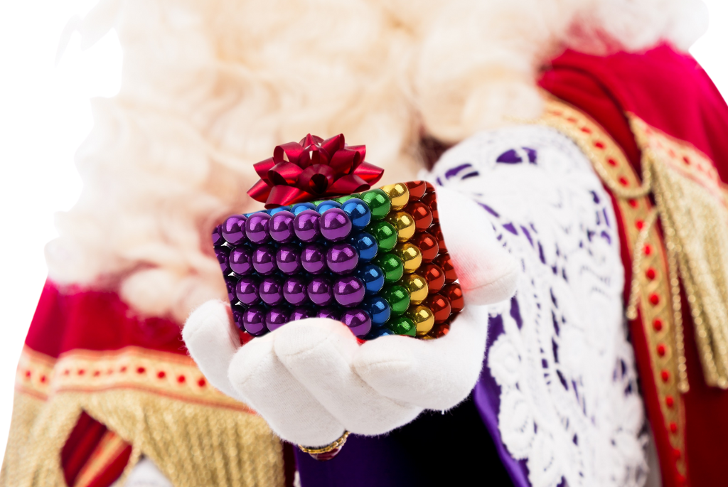 Sinterklaas die magneetballetjes vast heeft met een strik op.