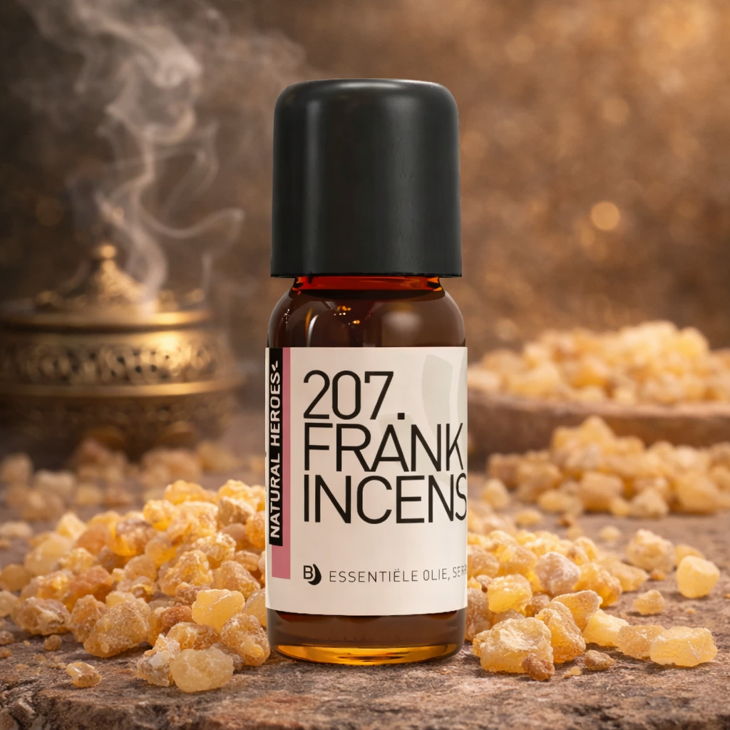 Een klein bruin glazen flesje met de tekst Natural Heroes essenstiële olie 207. Frank Incens. Het staat op een steen met stukjes geel wierrook errond en op de achtergrond een pot waar rook uitkomt.
